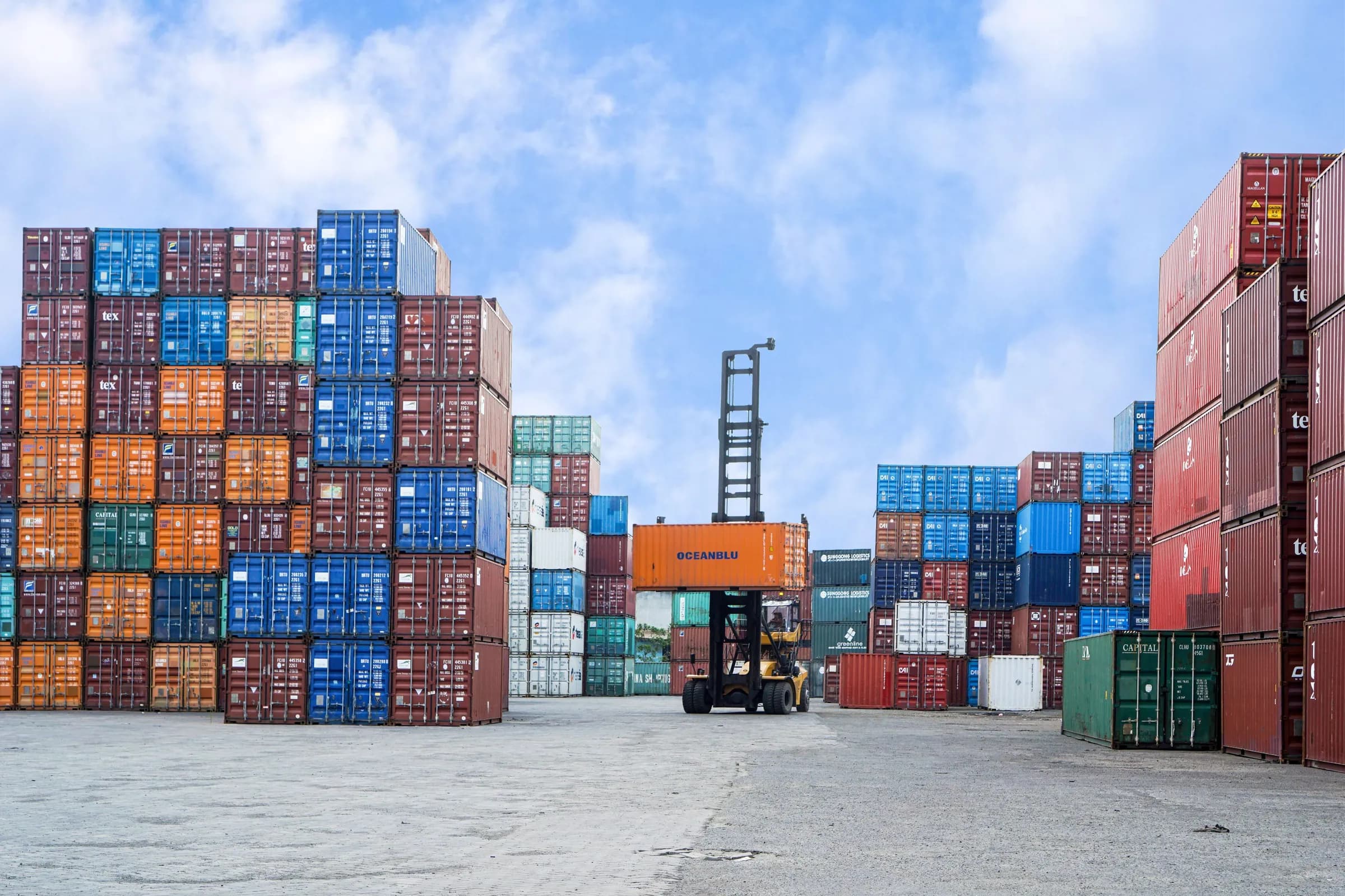 Stacked shipping containers and a forklift in a container yard
