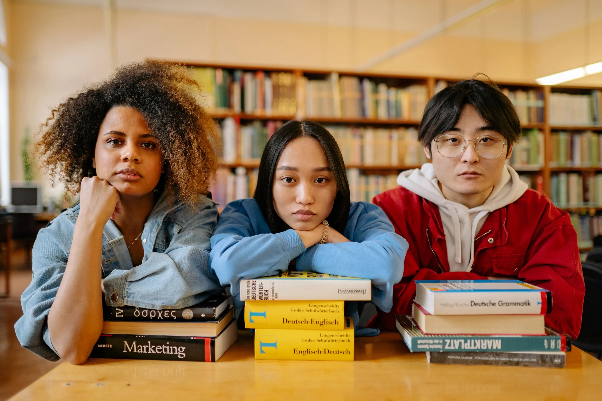 Three students with books in a library